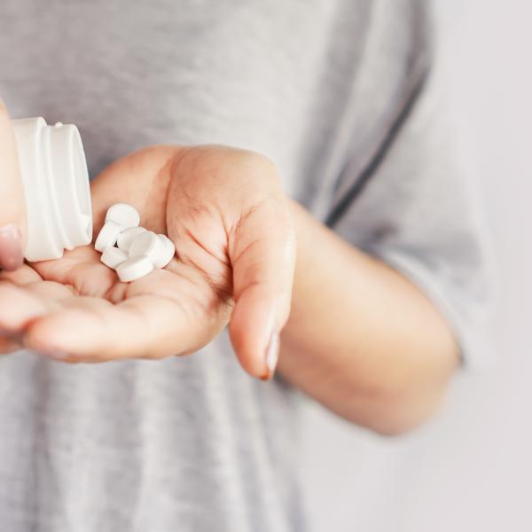 closeup woman hand holding medicine bottle taking overdose pills