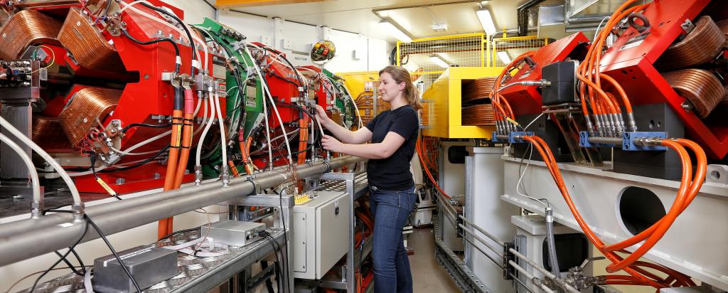 Woman standing next to accelerator transport line